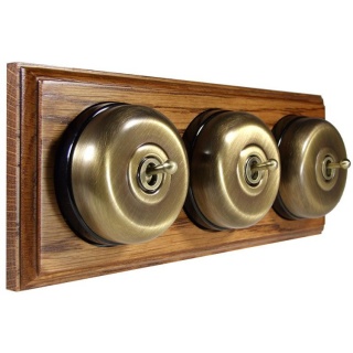 3 Gang 2 Way Antique Brass Smooth Dome With Black Pattress On Horizontal Med Oak Base